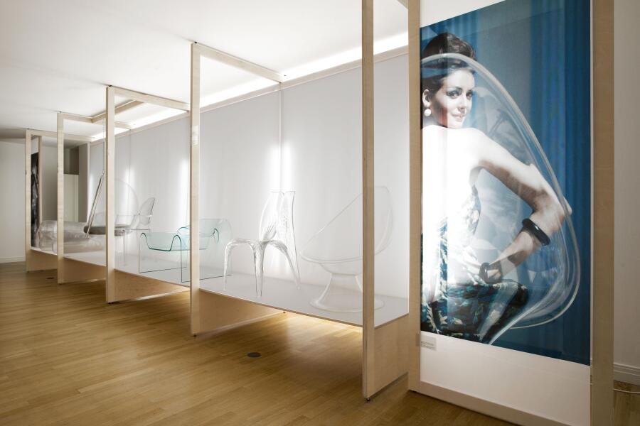 Blick in die Ausstellung "Welt aus Glas. Transparentes Design" im Wilhelm Wagenfeld Haus. Ausstellungsarchitektur mit transparenten Stühlen und Sesseln.