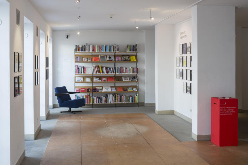 Ein Sessel steht vor einer Wand mit einem gut gefüllten Bücherregal