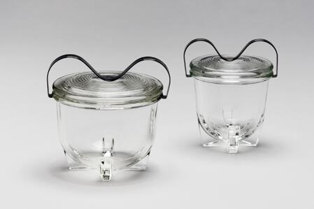 zwei Gefäße aus durchsichtigem Pressglas mit einem Metallbügel auf der Oberseite