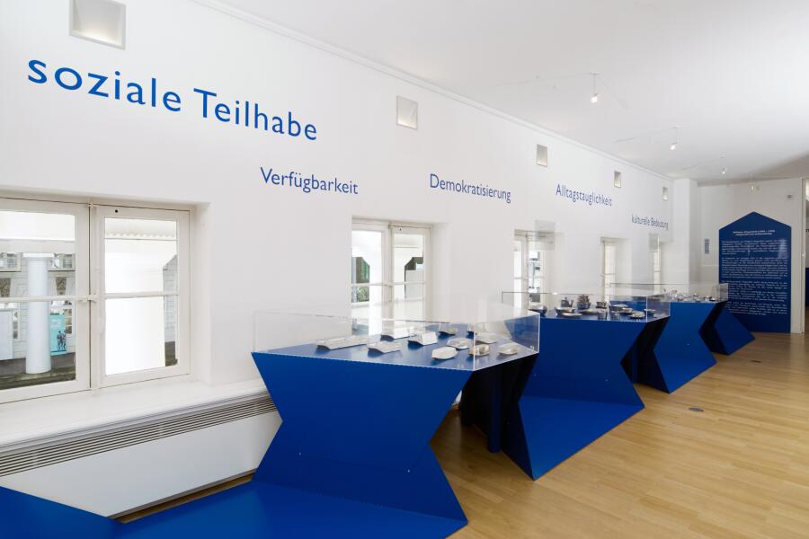 blaue Ausstellungsmodule wandern wie ein Band durch den Ausstellungsraum und bilden dabei Tischvitrinen.