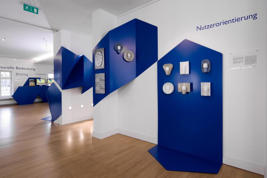 blaue Ausstellungsmodule wandern wie ein Band durch den Ausstellungsraum und bilden dabei Tischvitrinen.