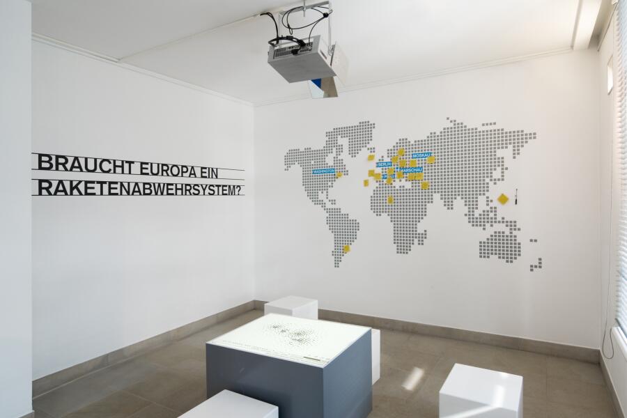 verschiedene Hocker stehen vor einer Wand mit einer großen Weltkarte