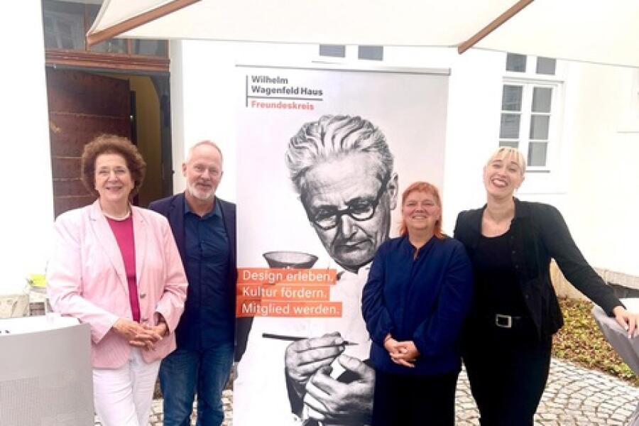 4 Personen haben sich um ein großes Portraitfoto von Wilhelm Wagenfeld gruppiert. 