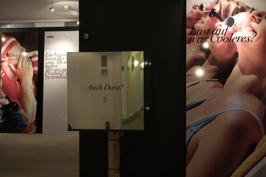 Großformatige Plakate und Spiegelelemente im Ausstellungsraum.