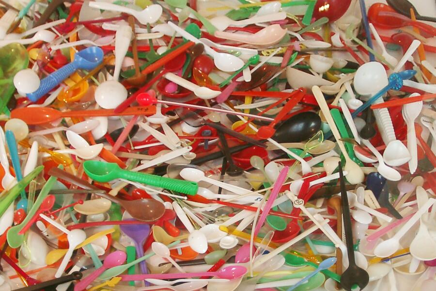 Hunderte unterschiedliche Kunststofflöffel liegen über und untereinander in einer Tischvitrine.