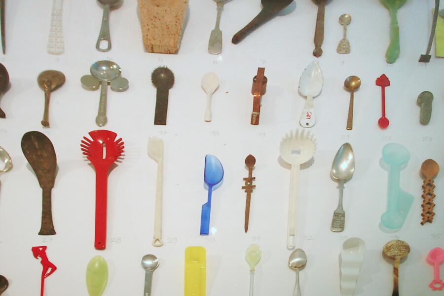 Viele Löffel in verschiedenen Farben, Formen und Materialien liegen nebeneinander in einer Tischvitrine